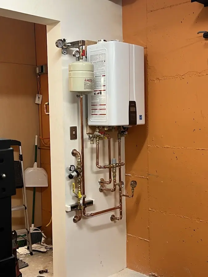 Plumbing technician inspecting water heater connections in Price
